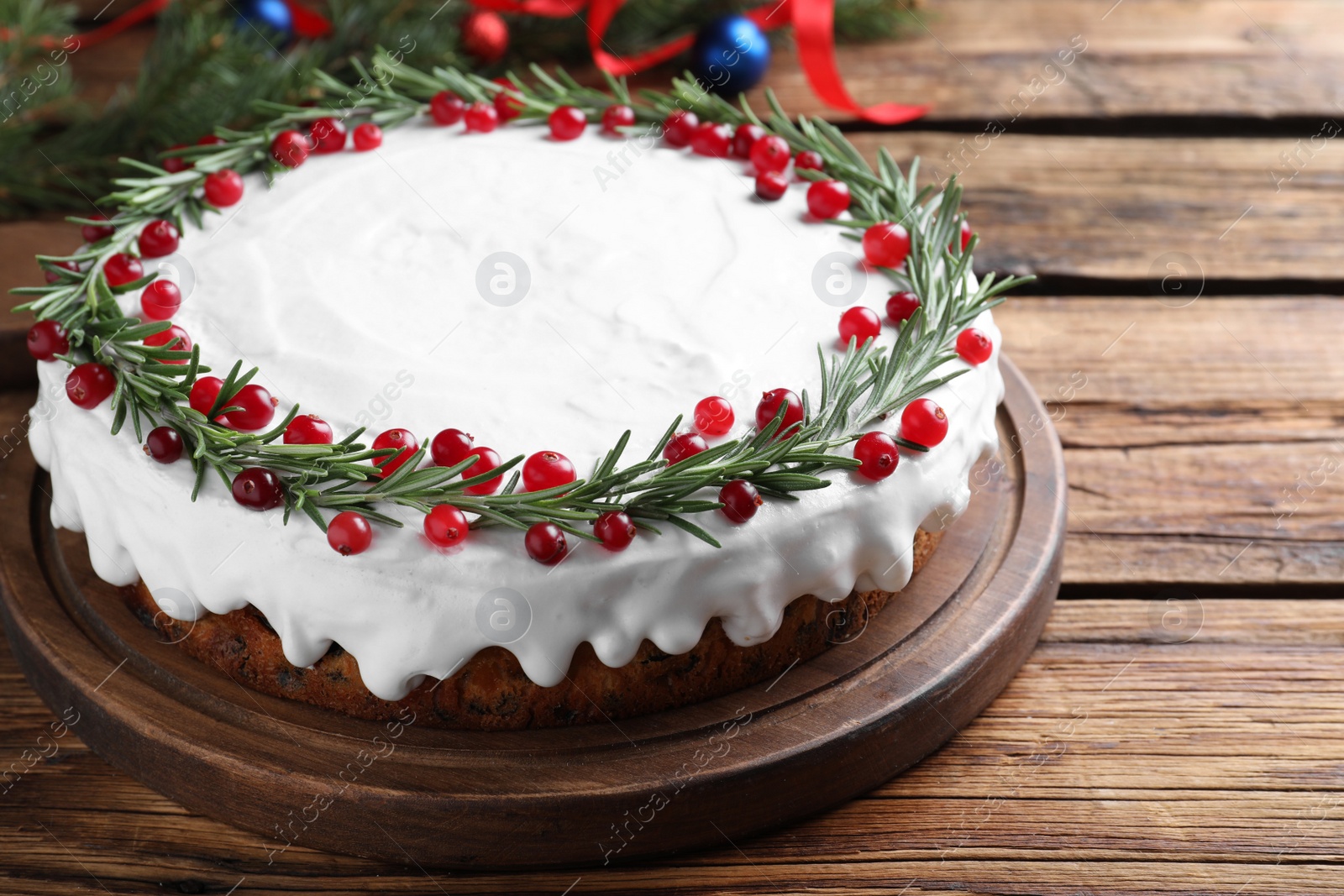 Traditional Christmas cake decorated with rosemary and cranberries on wooden table, closeup Photo of Traditional Christmas cake decorated with rosemary and cranberries on wooden table, closeup