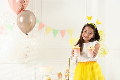 Cute little girl wearing fairy costume with popcorn in decorated room. Space for text Photo of Cute little girl wearing fairy costume with popcorn in decorated room. Space for text