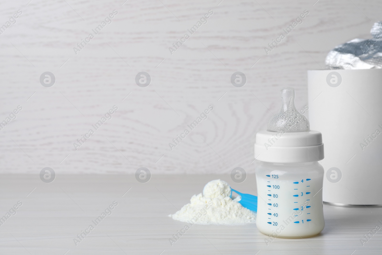 Powdered infant formula, scoop and feeding bottle on white wooden table, space for text. Baby milk Photo of Powdered infant formula, scoop and feeding bottle on white wooden table, space for text. Baby milk