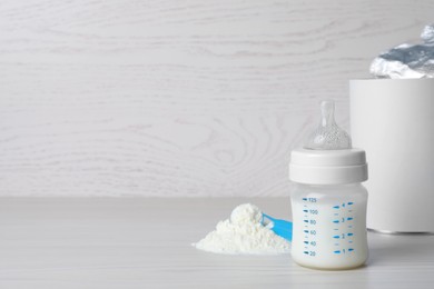 Powdered infant formula, scoop and feeding bottle on white wooden table, space for text. Baby milk Photo of Powdered infant formula, scoop and feeding bottle on white wooden table, space for text. Baby milk