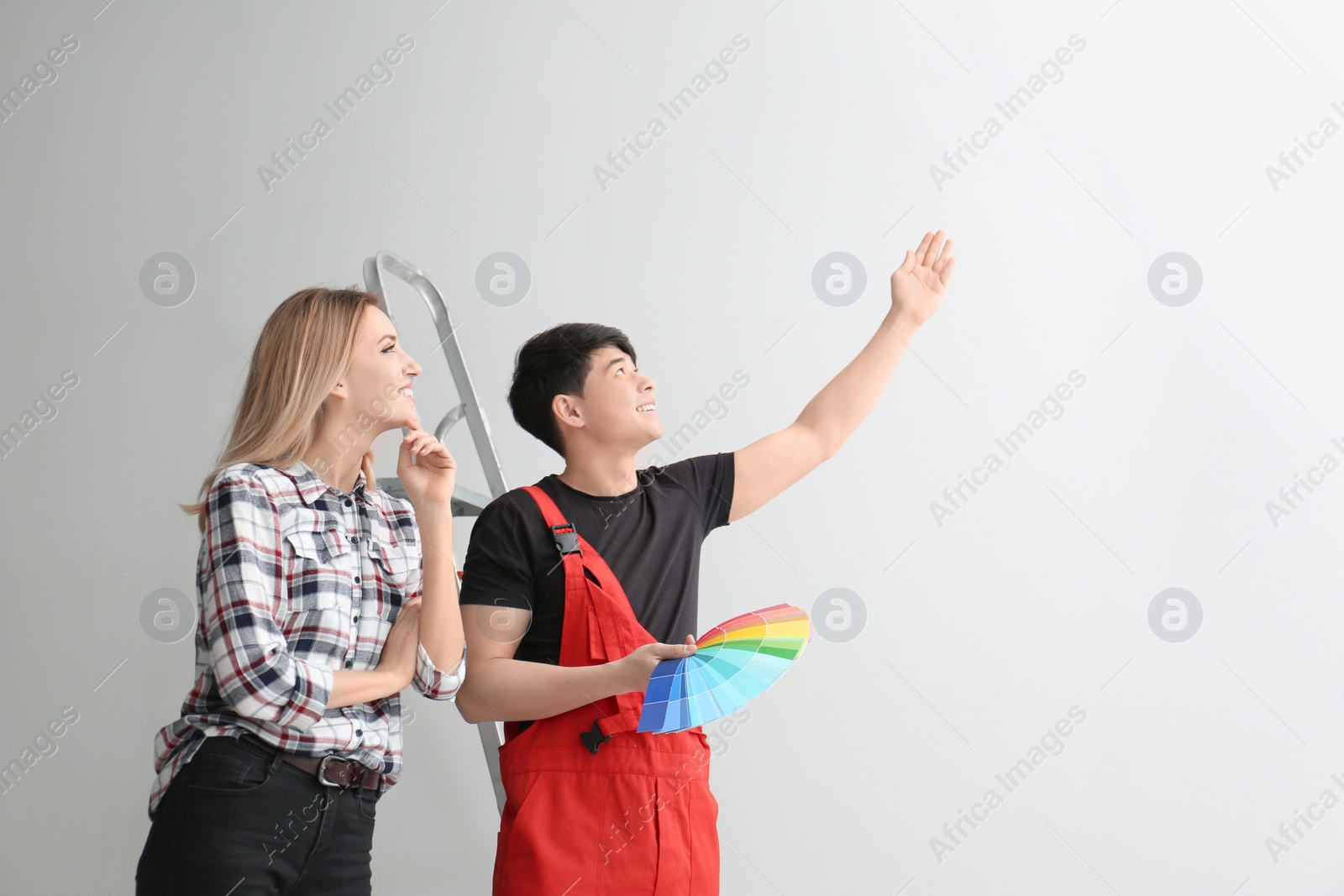 Male decorator and young woman choosing color for walls in empty room Photo of Male decorator and young woman choosing color for walls in empty room