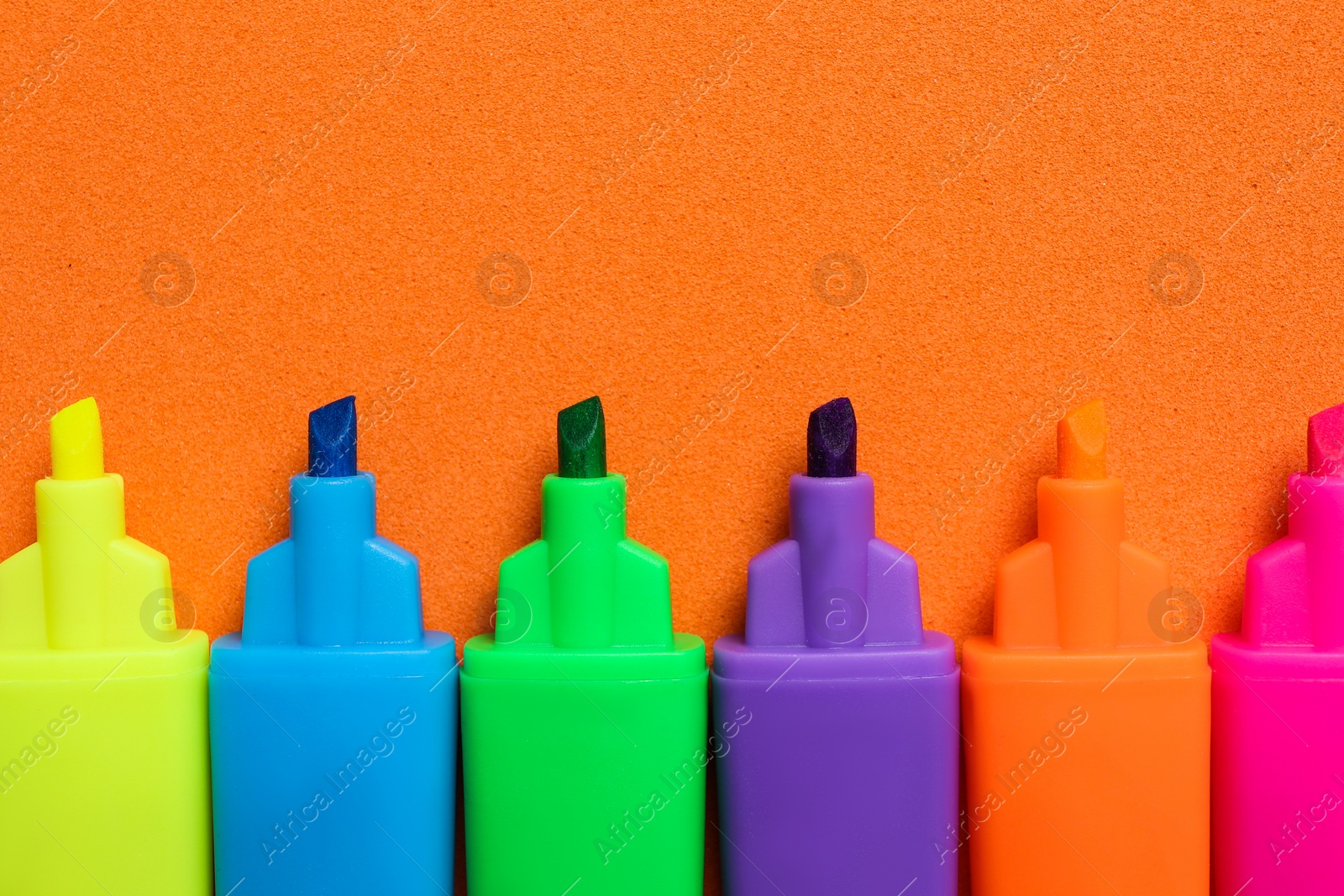 Photo of Set of highlighters on orange background, flat lay