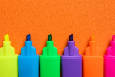 Photo of Set of highlighters on orange background, flat lay
