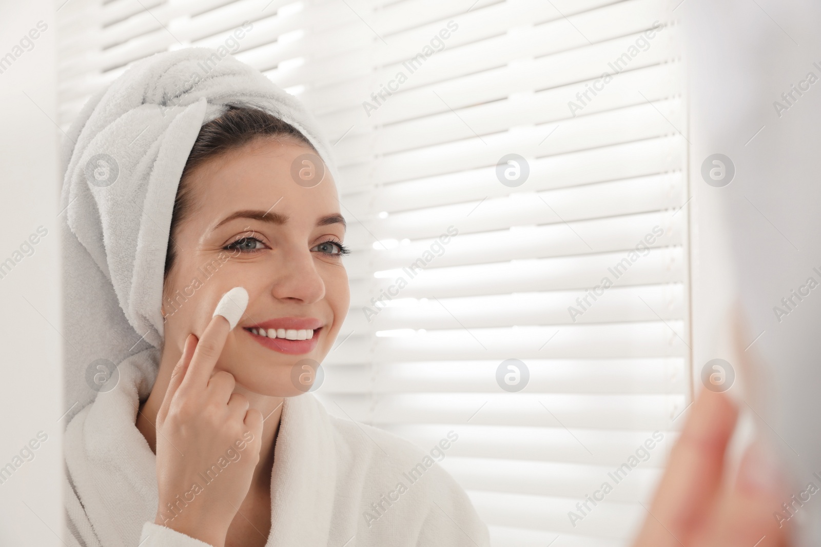 Woman using silkworm cocoon in skin care routine near mirror at home. Space for text Photo of Woman using silkworm cocoon in skin care routine near mirror at home. Space for text