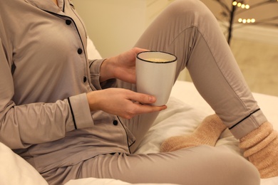 Woman in grey pajama holding cup of coffee indoors, closeup Photo of Woman in grey pajama holding cup of coffee indoors, closeup