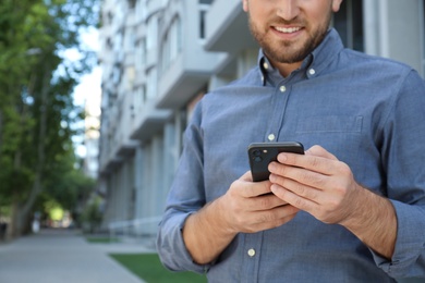 Young man with smartphone on city street, closeup Photo of Young man with smartphone on city street, closeup