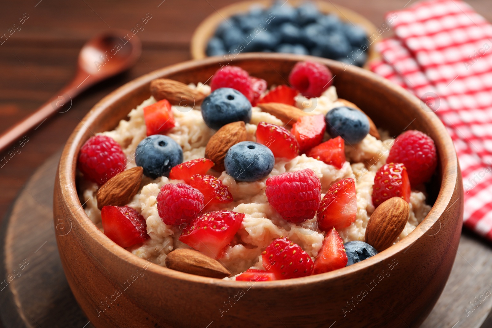 Tasty oatmeal porridge with berries and almond nuts in bowl served on table, closeup Photo of Tasty oatmeal porridge with berries and almond nuts in bowl served on table, closeup