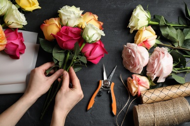 Woman making luxury bouquet of fresh roses at black table, top view Photo of Woman making luxury bouquet of fresh roses at black table, top view