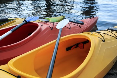 Modern kayaks with paddles on river, closeup. Summer camp activity Photo of Modern kayaks with paddles on river, closeup. Summer camp activity