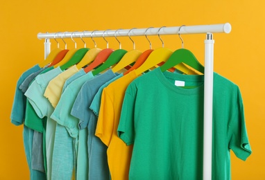 Rack with stylish children clothes on yellow background Photo of Rack with stylish children clothes on yellow background
