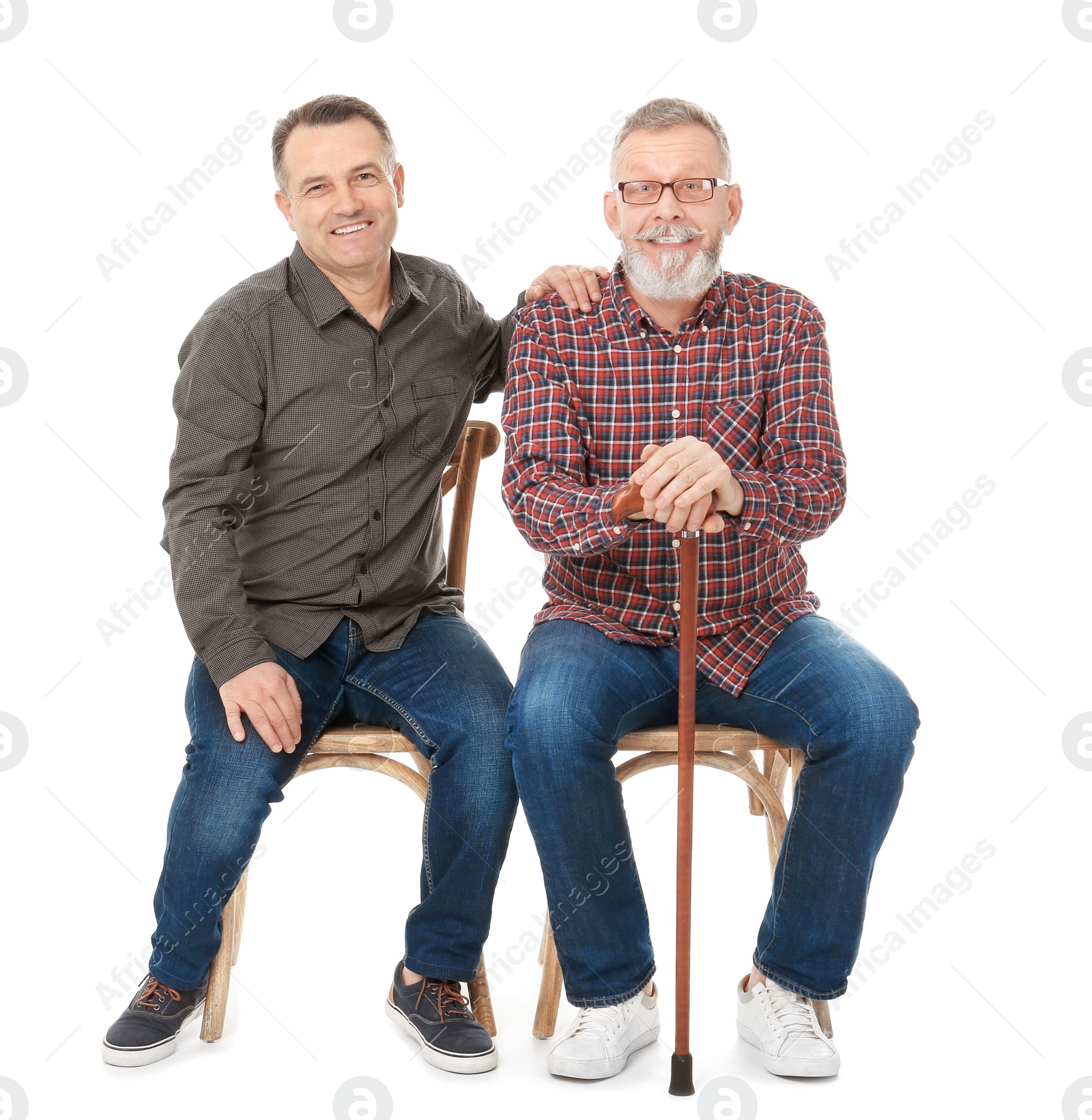 Happy senior men sitting on chairs against white background Photo of Happy senior men sitting on chairs against white background