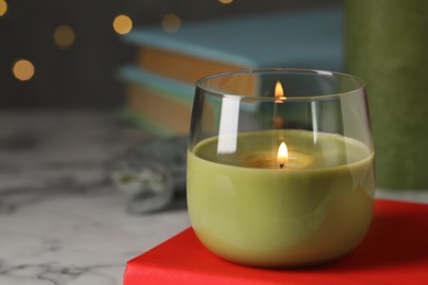 Burning candle and book on white marble table, space for text Photo of Burning candle and book on white marble table, space for text