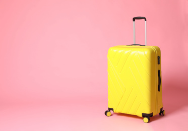 Photo of Stylish yellow suitcase on pink background. Space for text