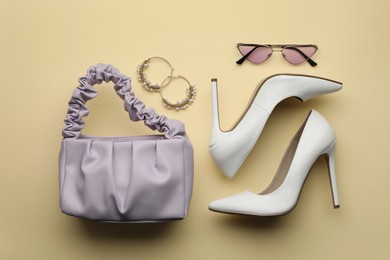 Stylish woman's bag, shoes, earrings and sunglasses on beige background, flat lay Photo of Stylish woman's bag, shoes, earrings and sunglasses on beige background, flat lay