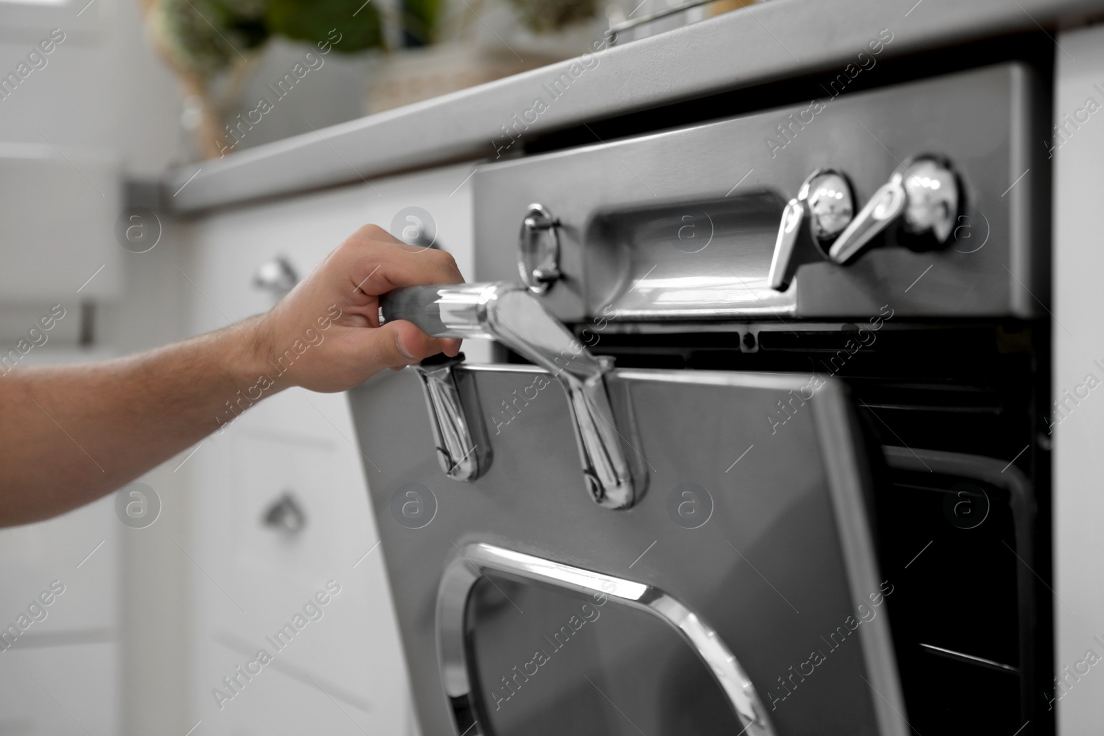 Man using modern oven in kitchen, closeup Photo of Man using modern oven in kitchen, closeup
