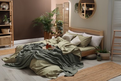 Stylish interior with large comfortable bed and potted plants Photo of Stylish interior with large comfortable bed and potted plants