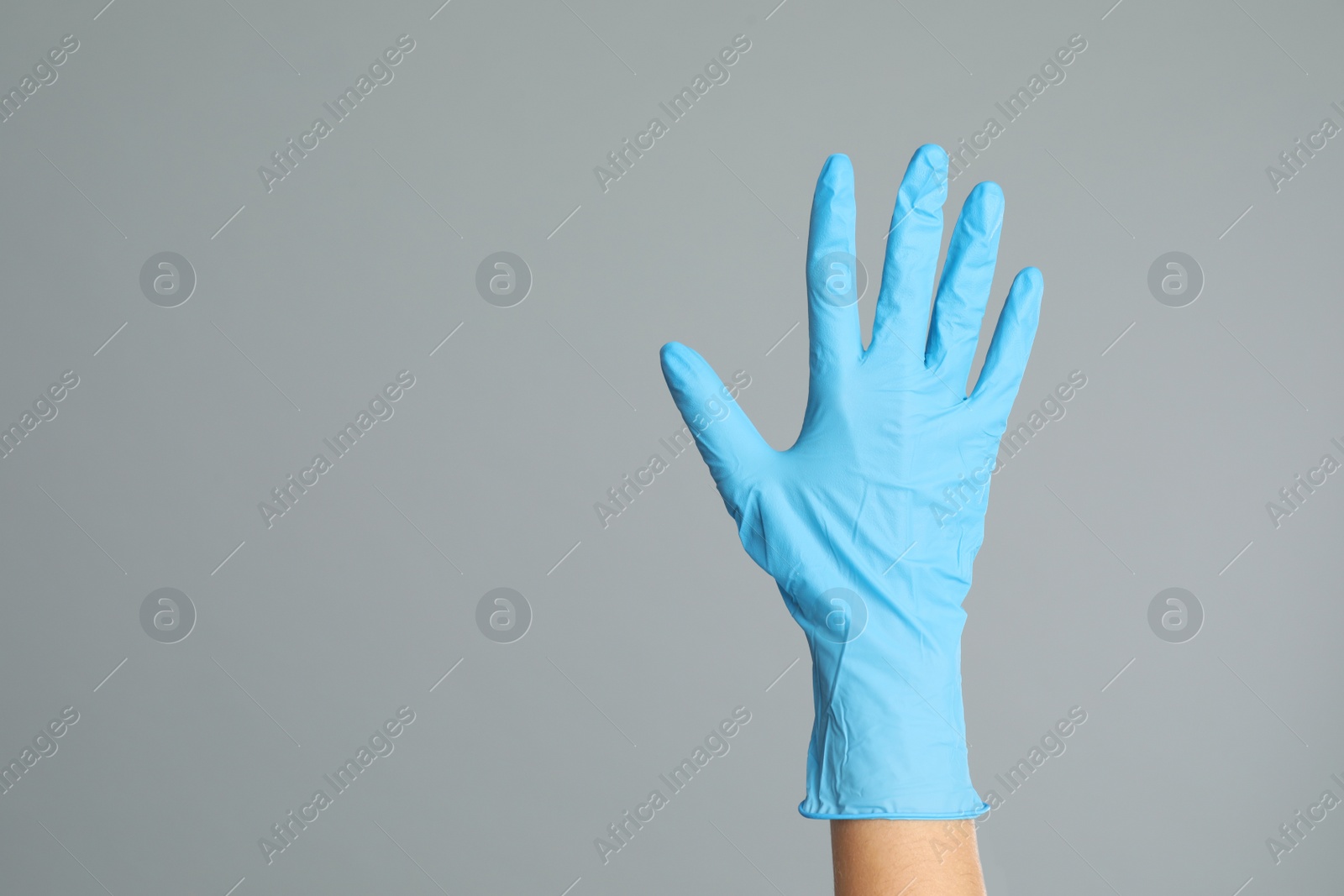 Doctor wearing medical gloves on grey background, closeup. Space for text Photo of Doctor wearing medical gloves on grey background, closeup. Space for text