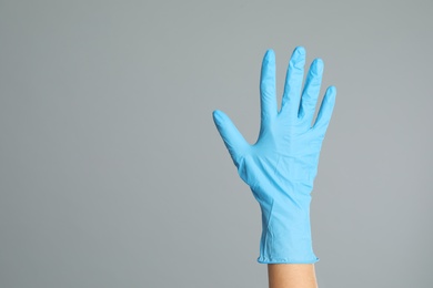 Doctor wearing medical gloves on grey background, closeup. Space for text Photo of Doctor wearing medical gloves on grey background, closeup. Space for text