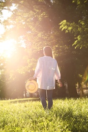 Young woman with straw hat outdoors on sunny day, back view Photo of Young woman with straw hat outdoors on sunny day, back view
