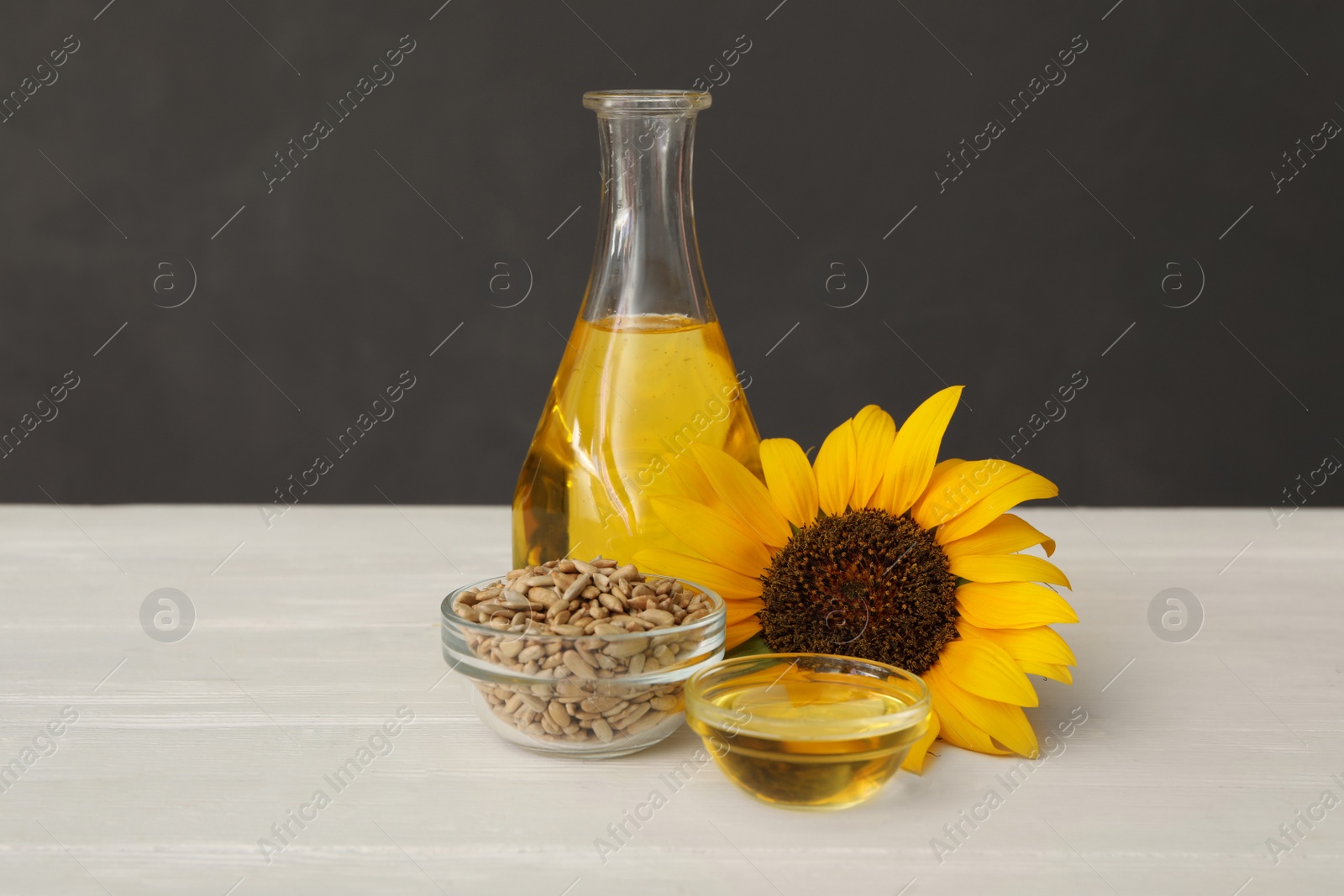 Sunflower, oil and seeds on white wooden table Photo of Sunflower, oil and seeds on white wooden table