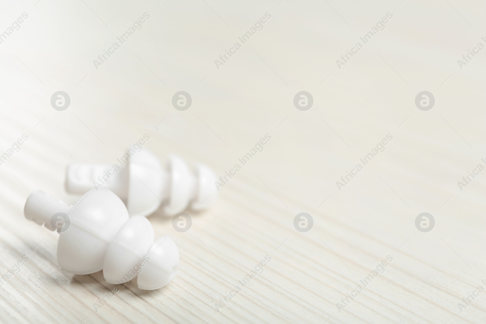 Pair of ear plugs on white wooden background, closeup. Space for text Photo of Pair of ear plugs on white wooden background, closeup. Space for text