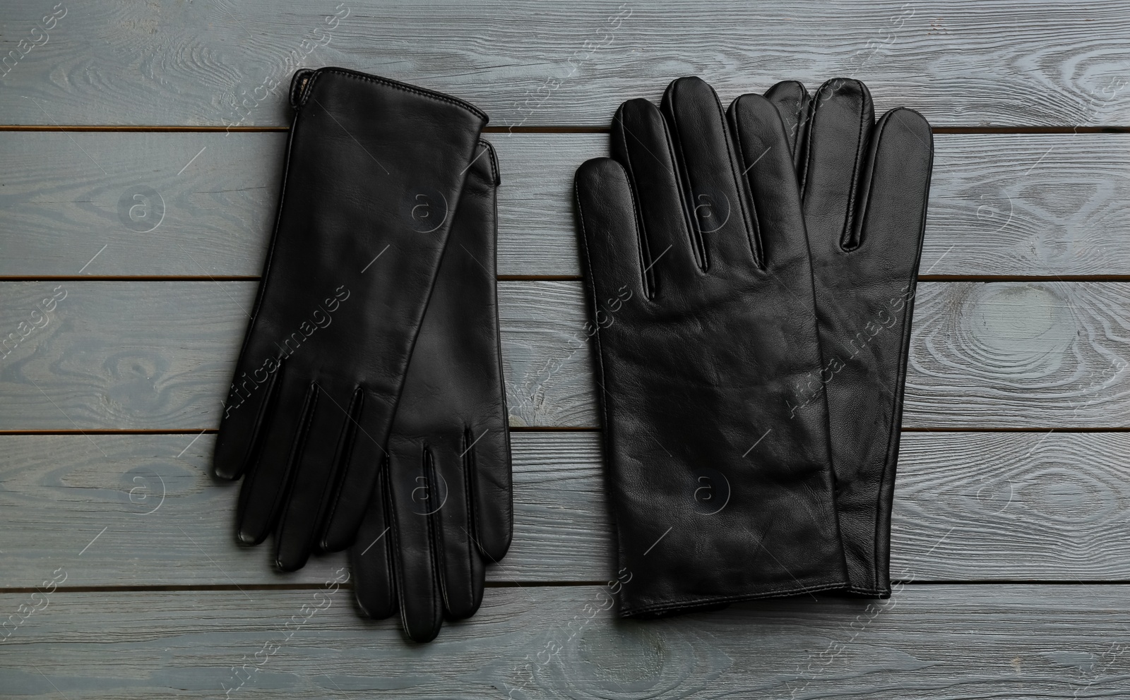 Stylish black leather gloves on grey wooden background, flat lay Photo of Stylish black leather gloves on grey wooden background, flat lay