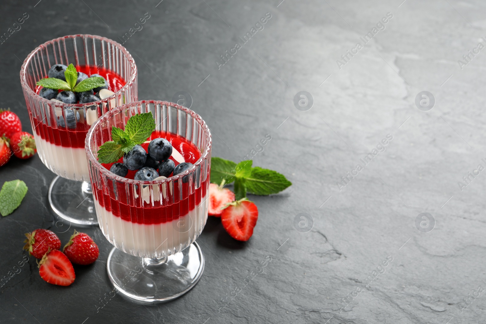 Delicious panna cotta with fruit coulis and fresh berries on dark grey table. Space for text Photo of Delicious panna cotta with fruit coulis and fresh berries on dark grey table. Space for text