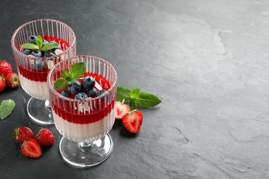 Delicious panna cotta with fruit coulis and fresh berries on dark grey table. Space for text Photo of Delicious panna cotta with fruit coulis and fresh berries on dark grey table. Space for text