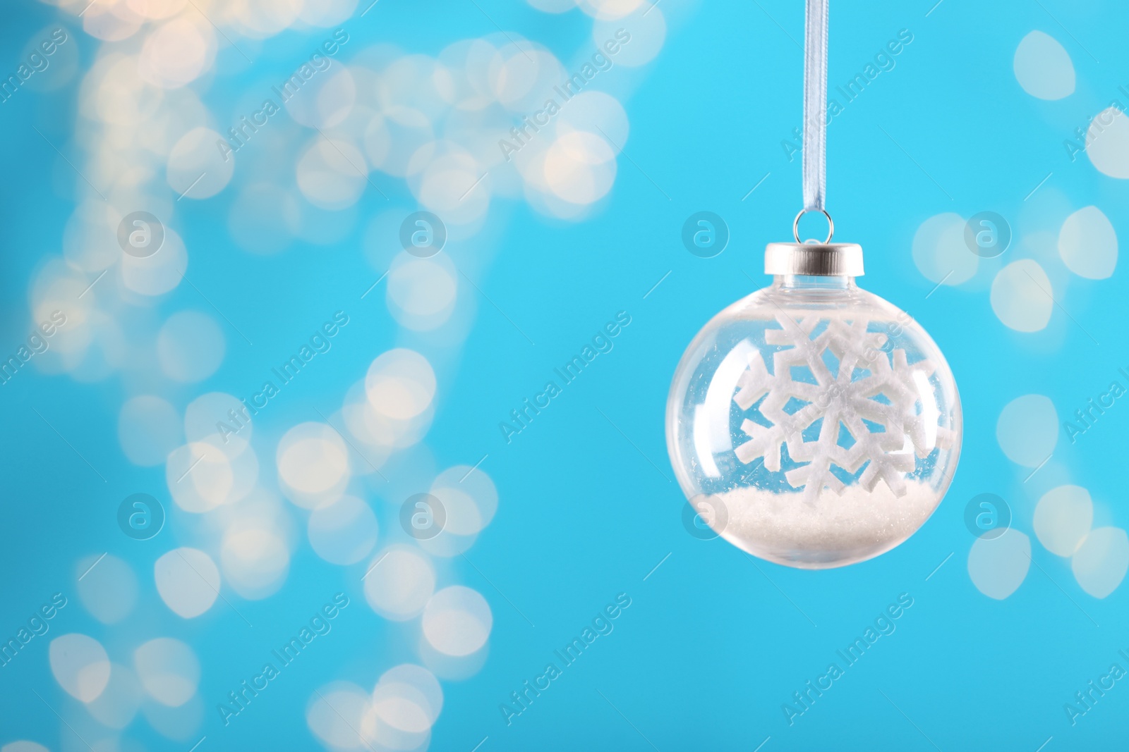 Decorative snow globe hanging on against blurred festive lights, space for text Photo of Decorative snow globe hanging on against blurred festive lights, space for text