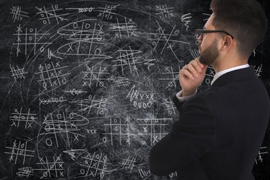 Young businessman in elegant suit near blackboard with drawn tic tac toe game Image of Young businessman in elegant suit near blackboard with drawn tic tac toe game