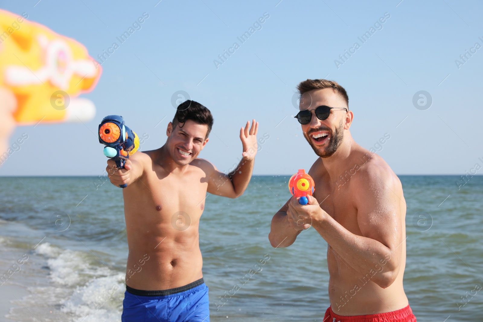 Friends with water guns having fun on beach Photo of Friends with water guns having fun on beach