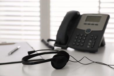 Headset on white table in office, space for text. Hotline service Photo of Headset on white table in office, space for text. Hotline service