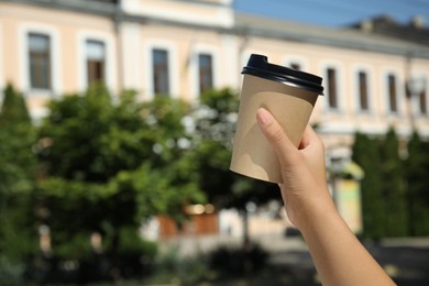 Woman holding takeaway cardboard coffee cup with plastic lid outdoors, closeup Photo of Woman holding takeaway cardboard coffee cup with plastic lid outdoors, closeup
