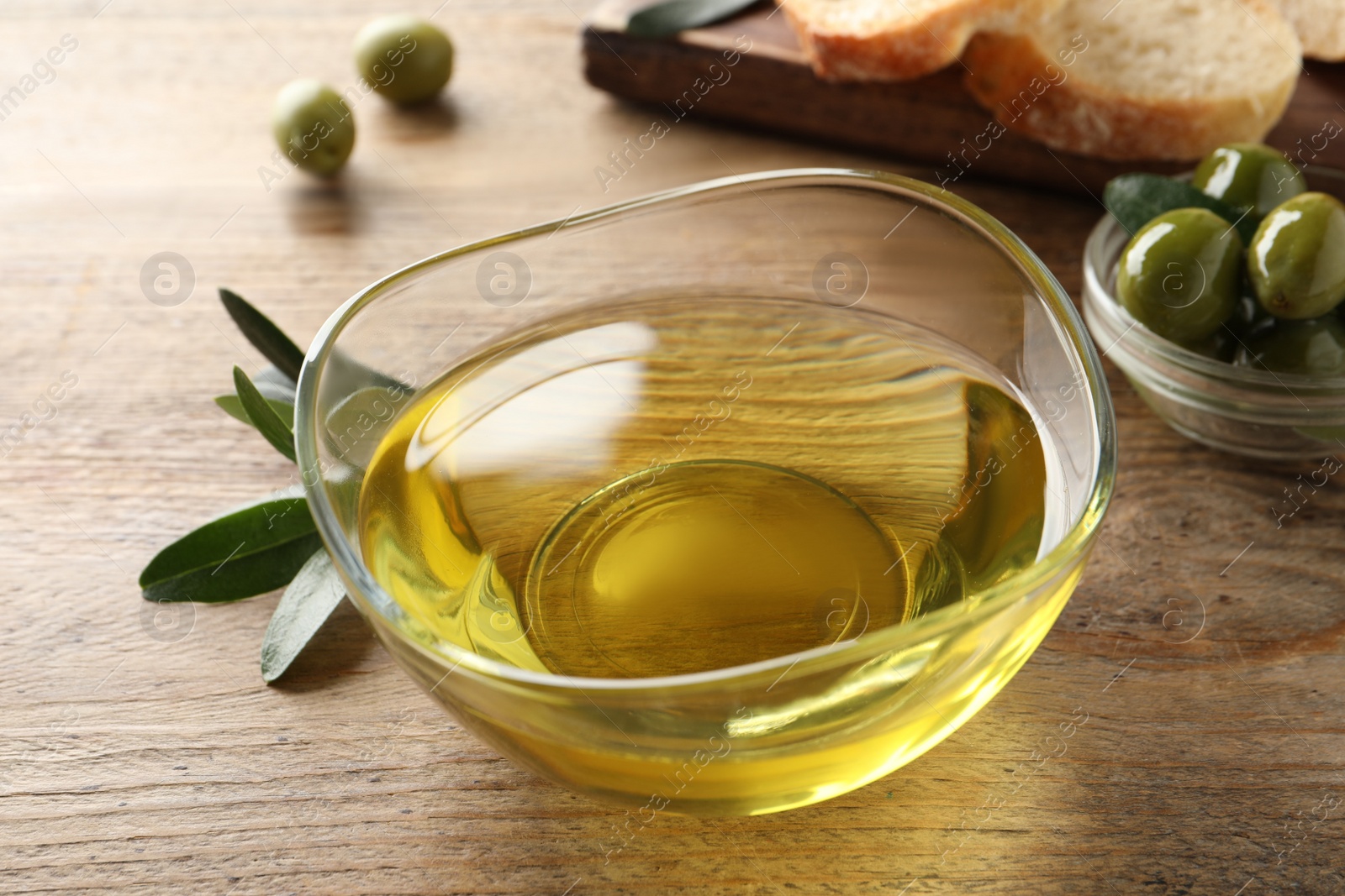 Glass bowl of olive oil on wooden table, closeup Photo of Glass bowl of olive oil on wooden table, closeup