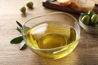 Glass bowl of olive oil on wooden table, closeup Photo of Glass bowl of olive oil on wooden table, closeup