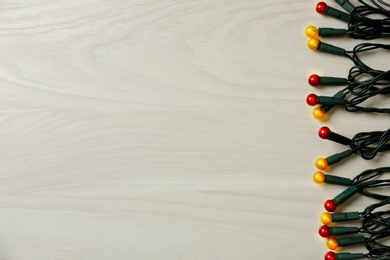 Beautiful glowing Christmas lights on white wooden background, top view. Space for text Photo of Beautiful glowing Christmas lights on white wooden background, top view. Space for text