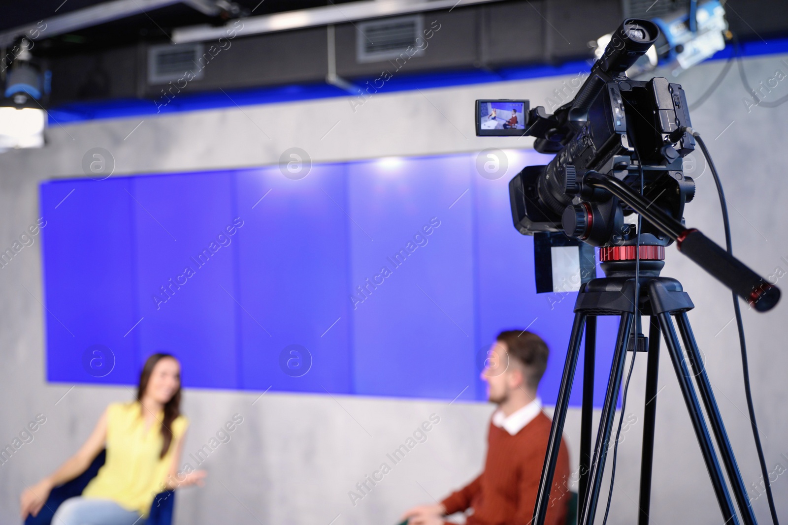 Photo of Presenters working in studio, focus on video camera
