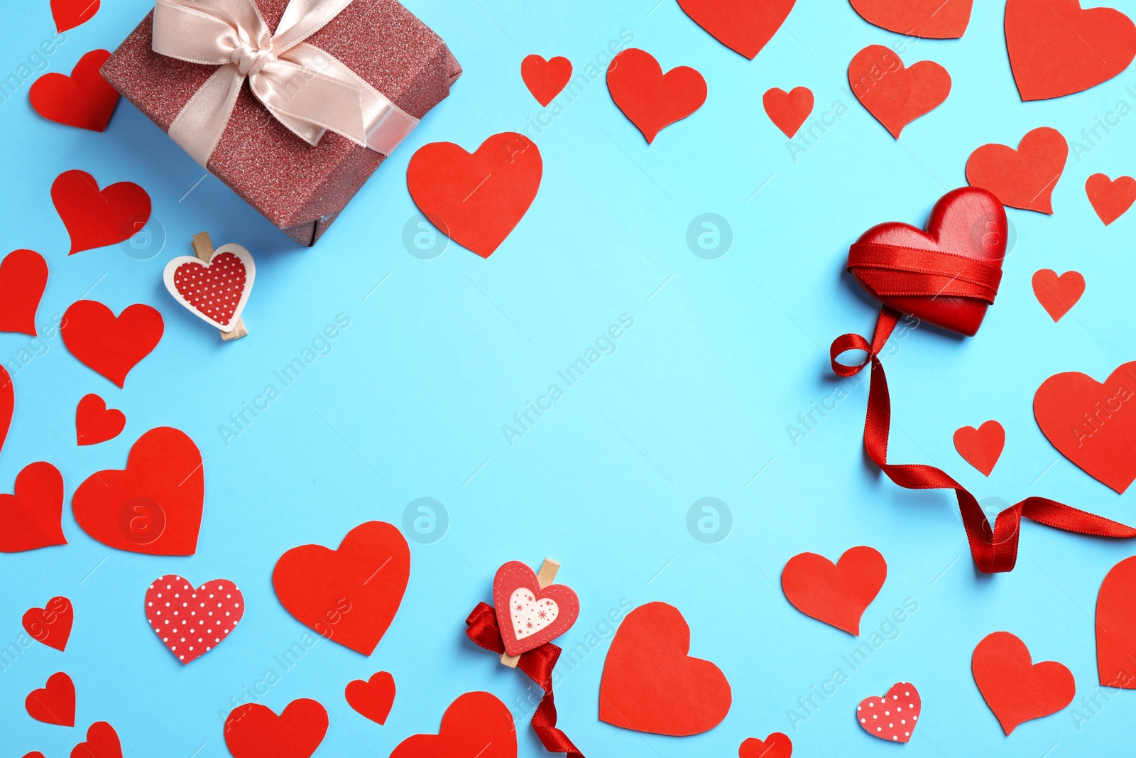 Flat lay composition with red hearts and gift on light blue background. Space for text Photo of Flat lay composition with red hearts and gift on light blue background. Space for text