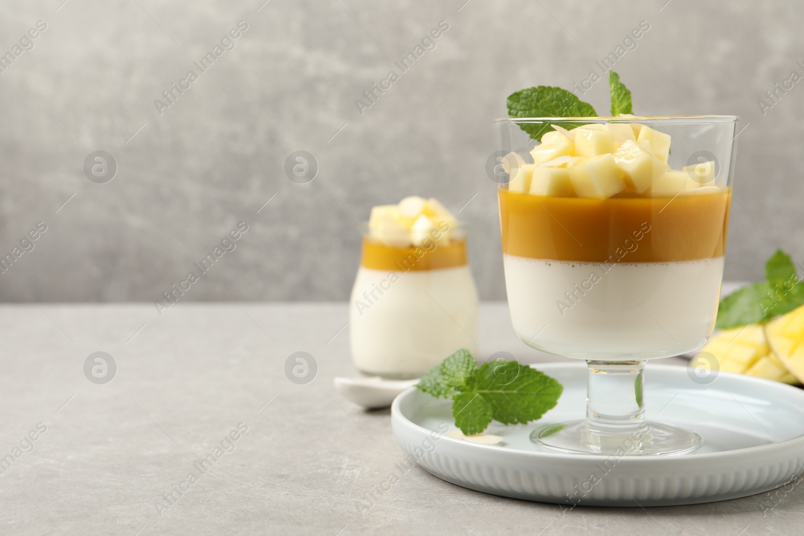 Delicious panna cotta with mango on grey table. Space for text Photo of Delicious panna cotta with mango on grey table. Space for text