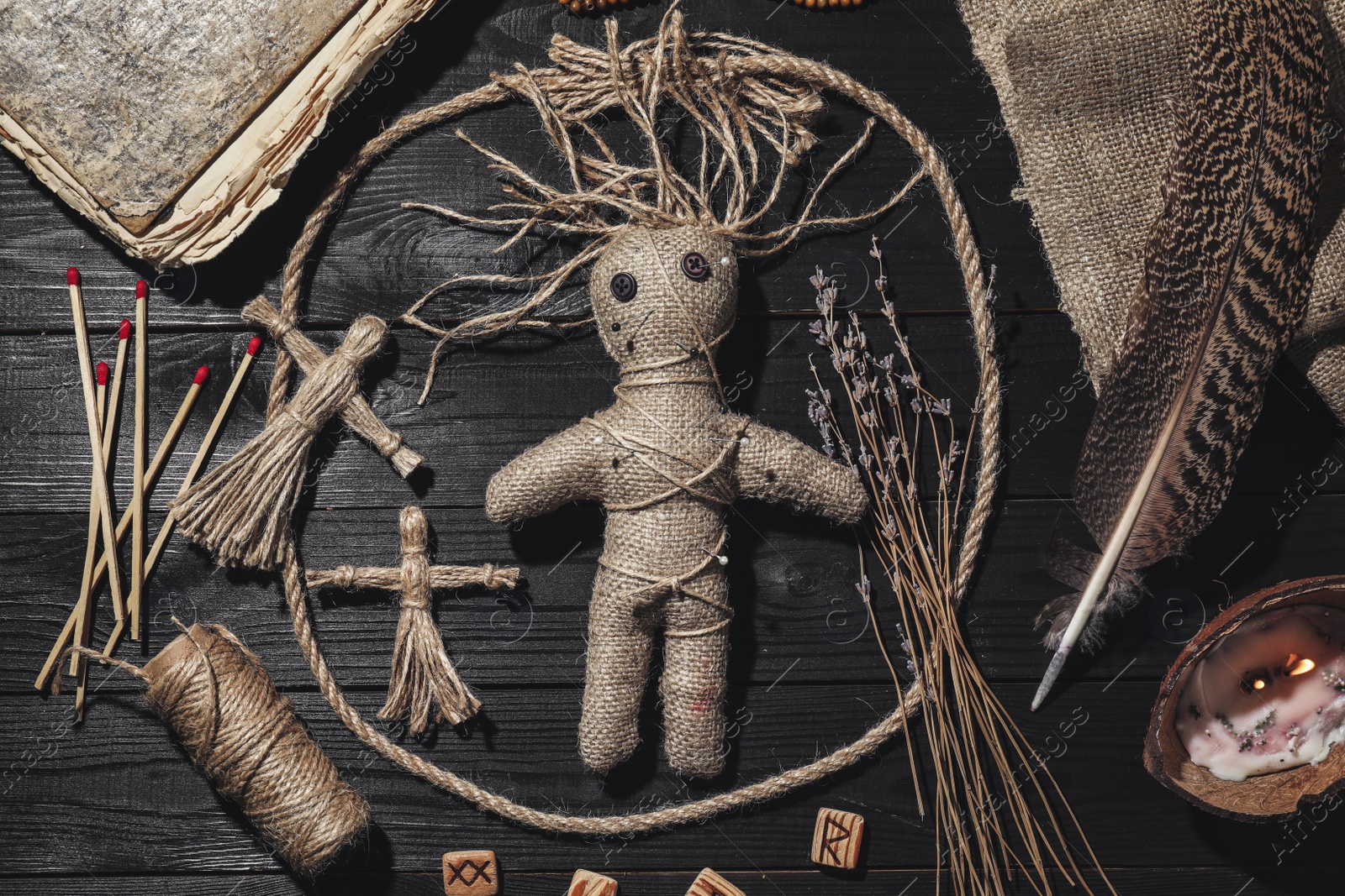 Female voodoo doll with pins surrounded by ceremonial items on black wooden background, flat lay Photo of Female voodoo doll with pins surrounded by ceremonial items on black wooden background, flat lay