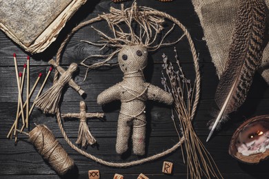 Female voodoo doll with pins surrounded by ceremonial items on black wooden background, flat lay Photo of Female voodoo doll with pins surrounded by ceremonial items on black wooden background, flat lay