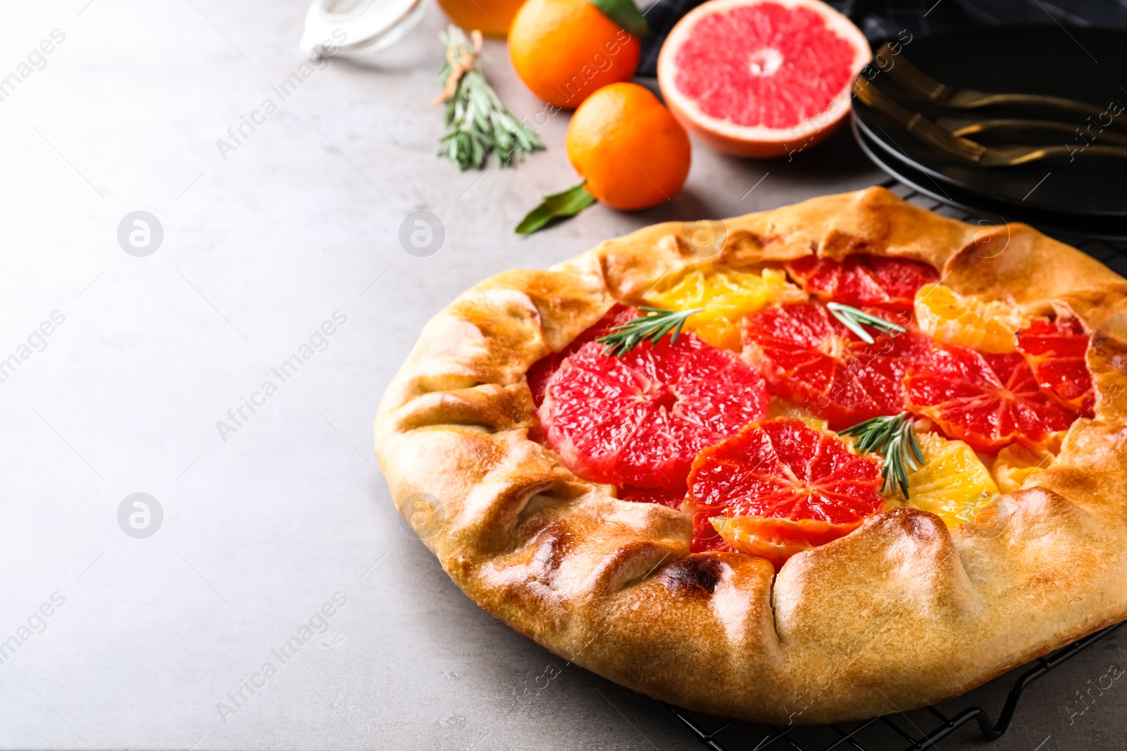 Tasty galette with citrus fruits and rosemary on light grey table. Space for text Photo of Tasty galette with citrus fruits and rosemary on light grey table. Space for text