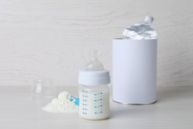 Blank can of powdered infant formula with scoop and feeding bottle on white wooden table. Baby milk Photo of Blank can of powdered infant formula with scoop and feeding bottle on white wooden table. Baby milk