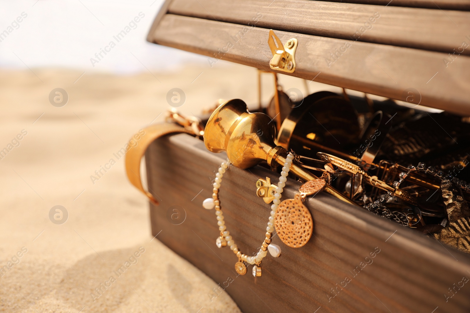 Open wooden treasure chest on sandy beach, closeup Photo of Open wooden treasure chest on sandy beach, closeup