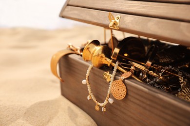 Open wooden treasure chest on sandy beach, closeup Photo of Open wooden treasure chest on sandy beach, closeup