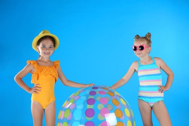 Cute little children in beachwear with inflatable ball on light blue background Photo of Cute little children in beachwear with inflatable ball on light blue background