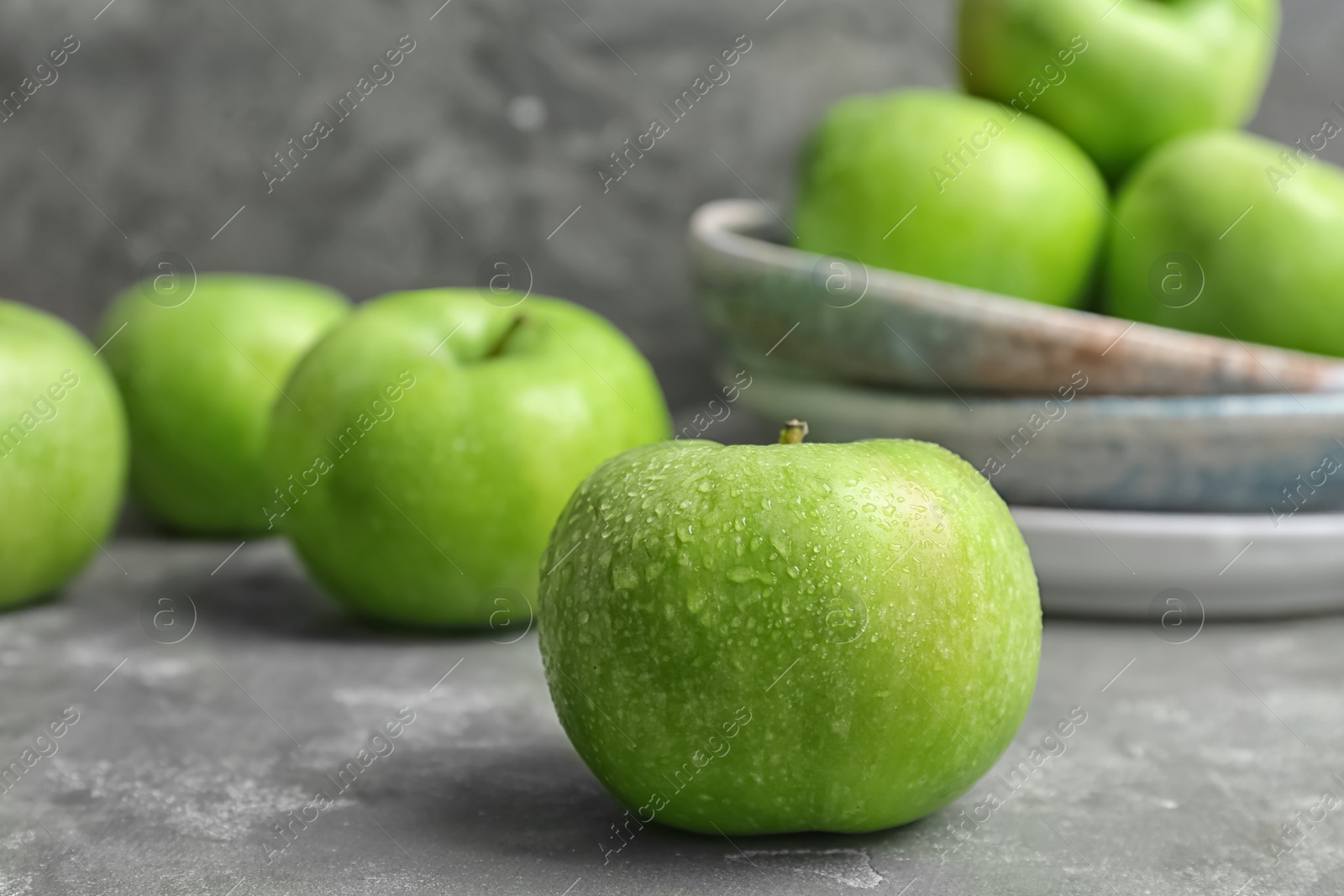 Fresh green apple with water drops on grey table Photo of Fresh green apple with water drops on grey table