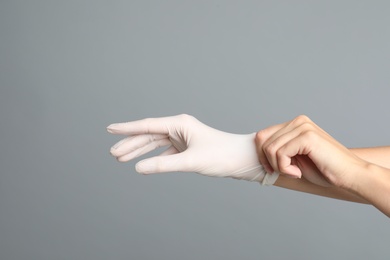 Doctor wearing medical gloves on grey background, closeup Photo of Doctor wearing medical gloves on grey background, closeup
