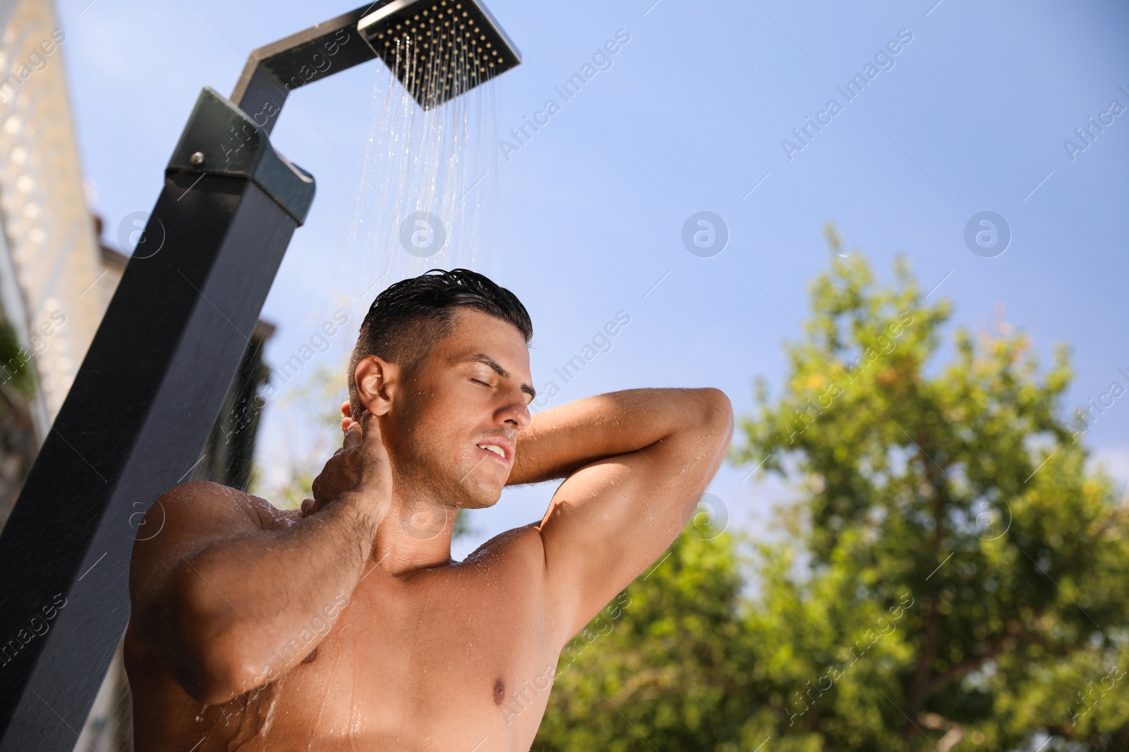 Man washing hair in outdoor shower on summer day Photo of Man washing hair in outdoor shower on summer day