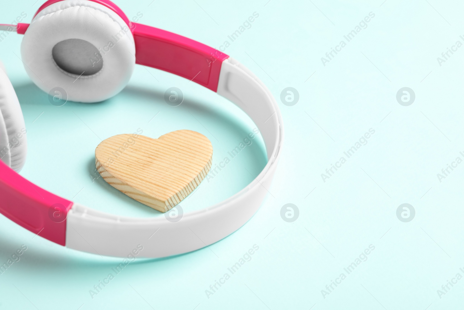Modern headphones and wooden heart on turquoise background, space for text. Listening love music songs Photo of Modern headphones and wooden heart on turquoise background, space for text. Listening love music songs